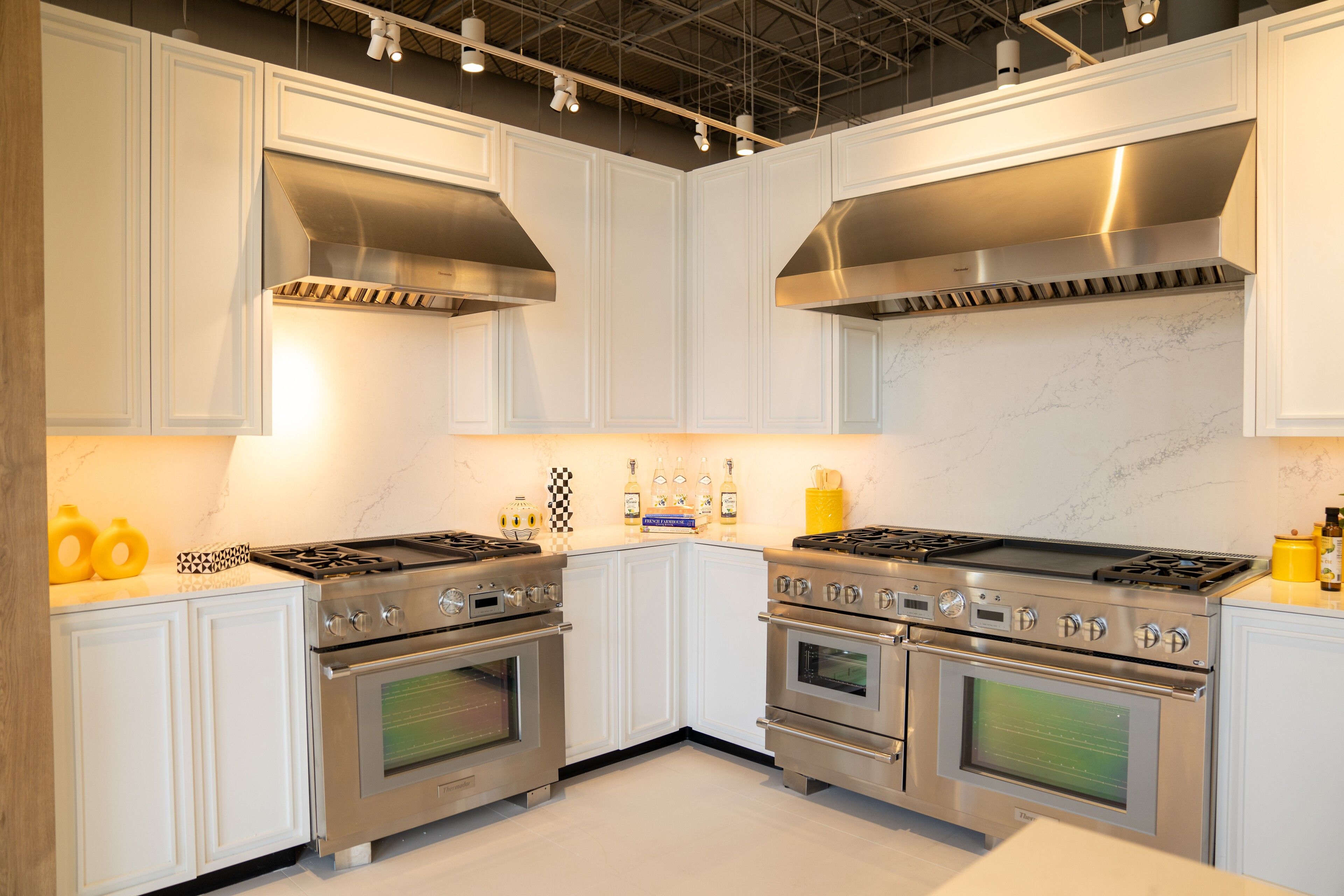 White painted cabinetry with twin ranges and a marble backsplash - custom cabinetry by NIC Cabinetry