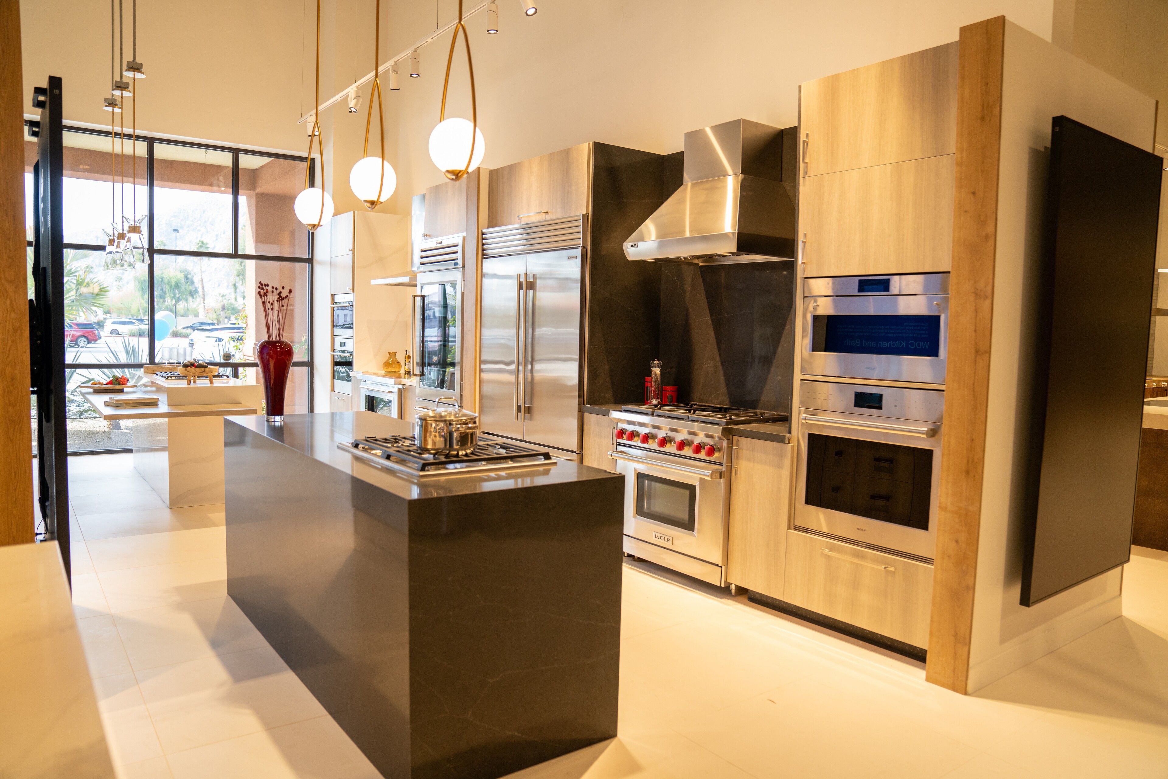 Light oak cabinetry framing a dark waterfall island and cooktop