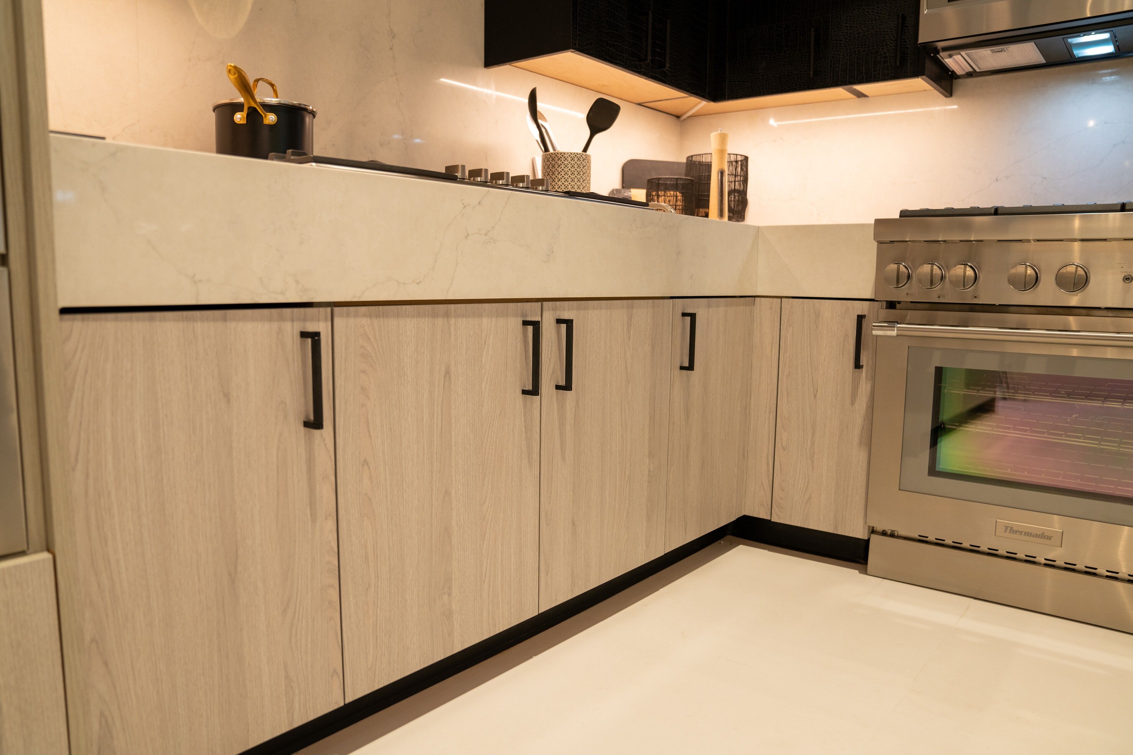 Warm greige-oak cabinetry wrapping to a dark waterfall island