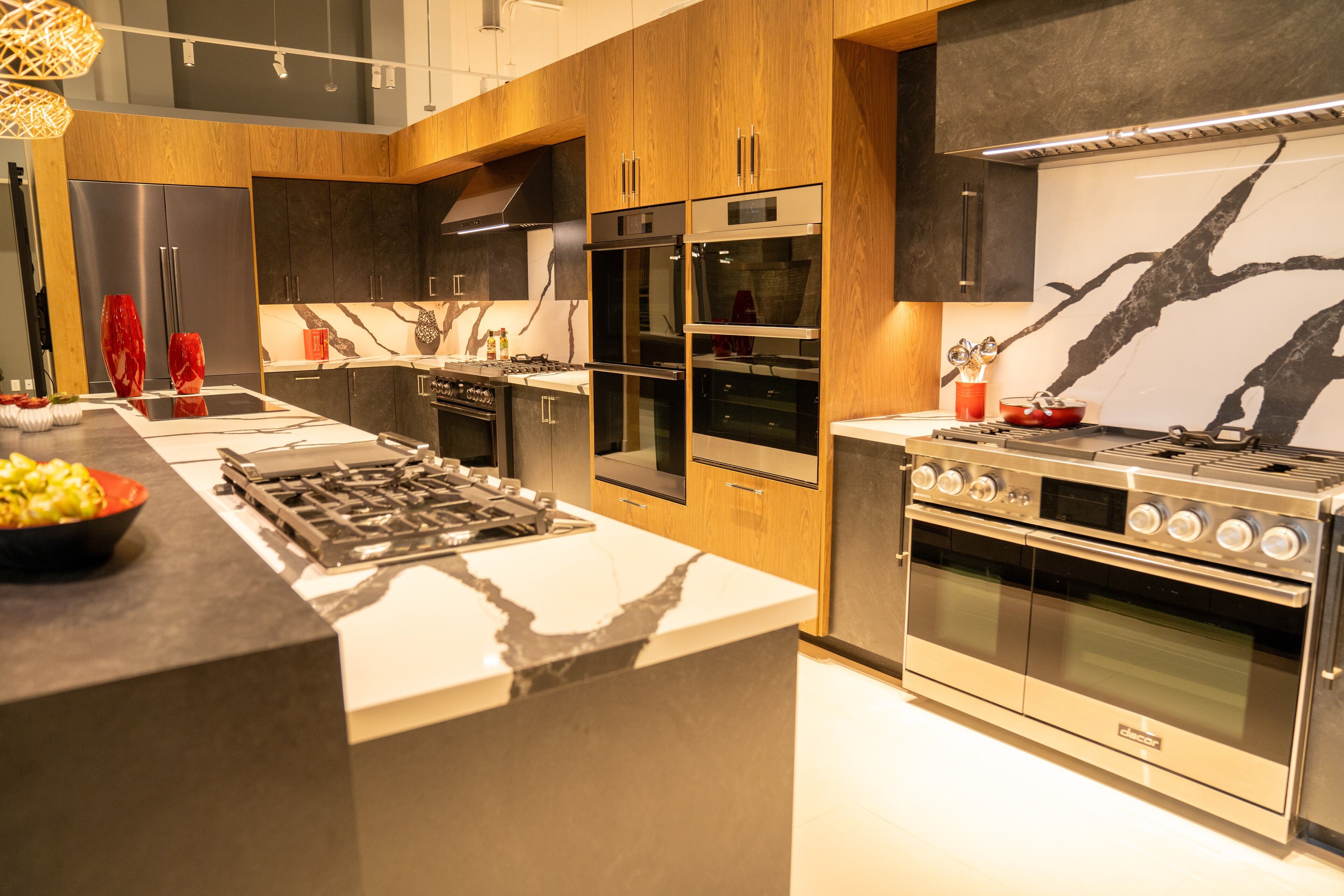 A bold marble waterfall island and cooktop set against walnut cabinetry - custom cabinetry by NIC Cabinetry