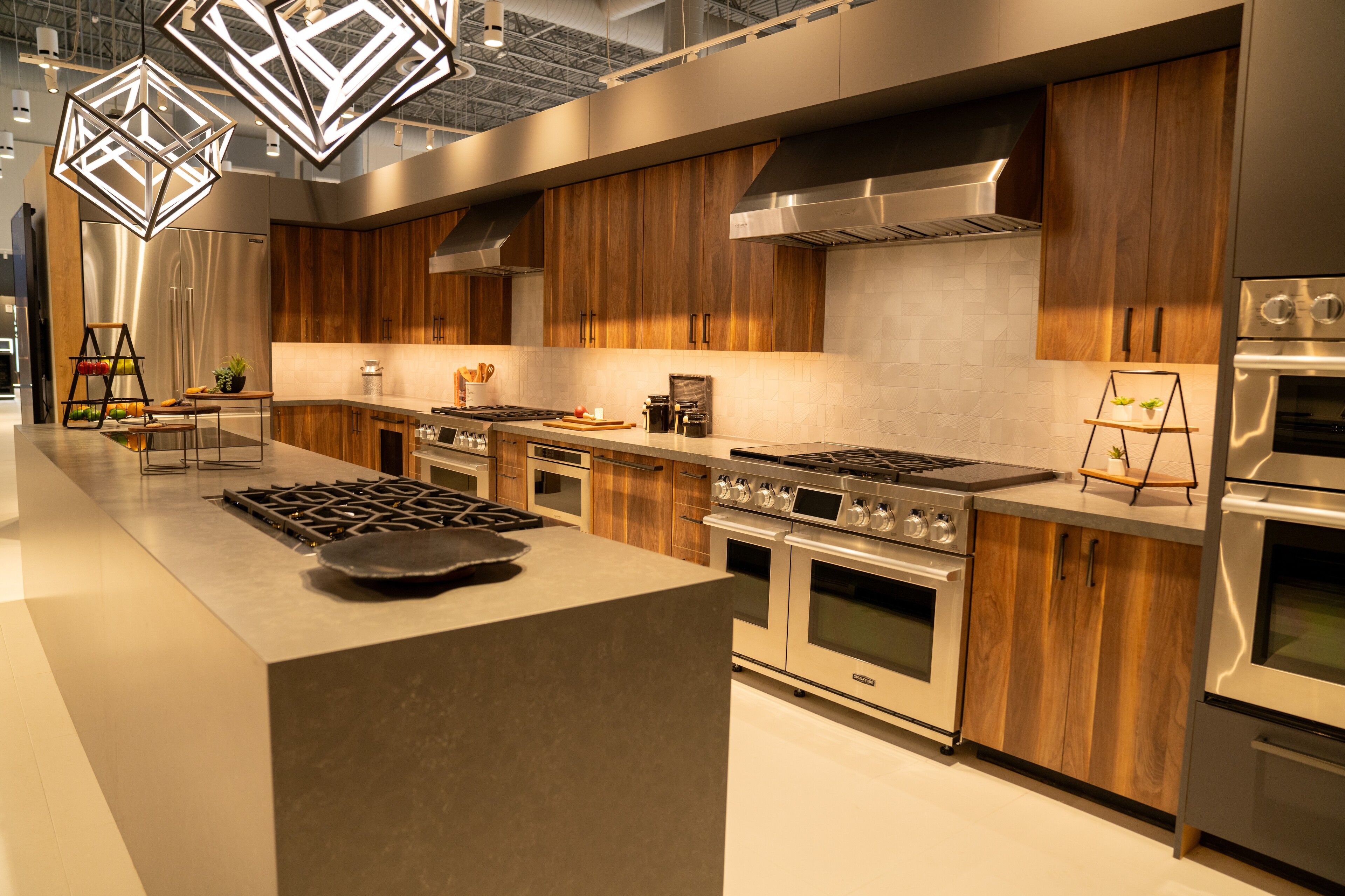 Walnut cabinetry, a quartz waterfall island and geometric cage pendants