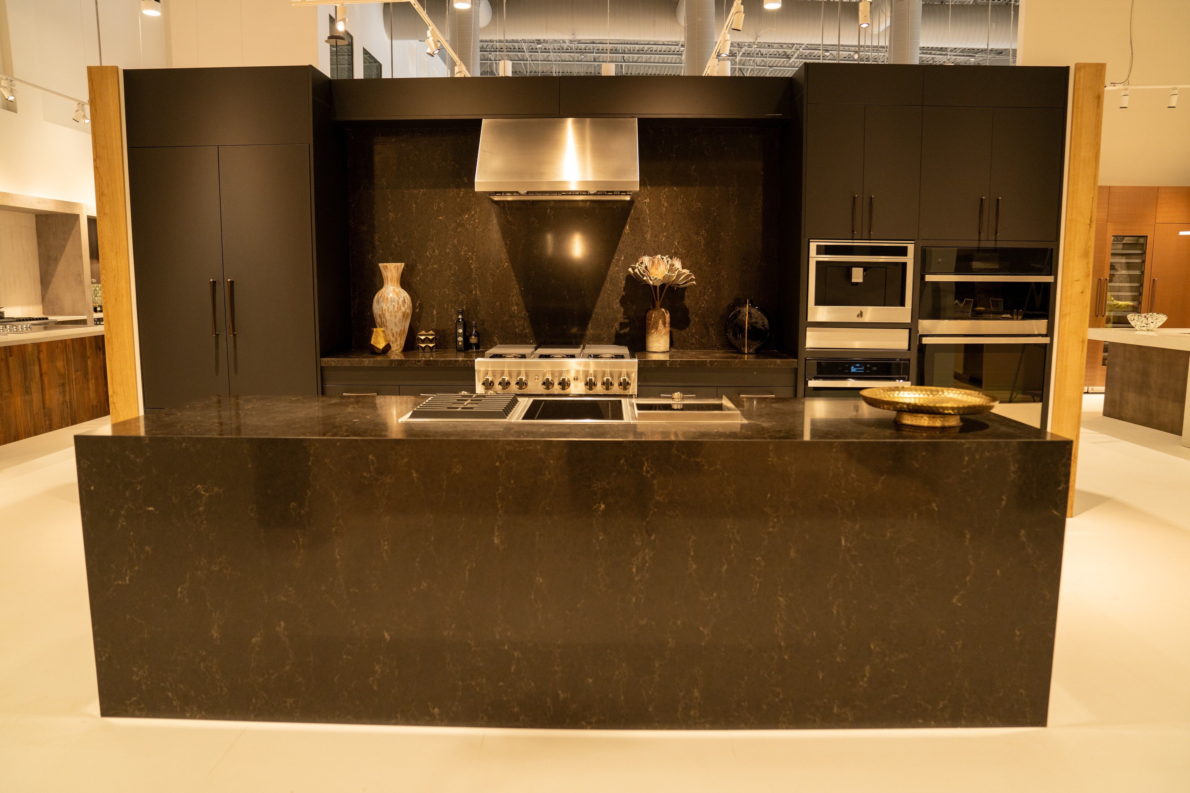 Black slab and walnut cabinetry with a dark stone waterfall island