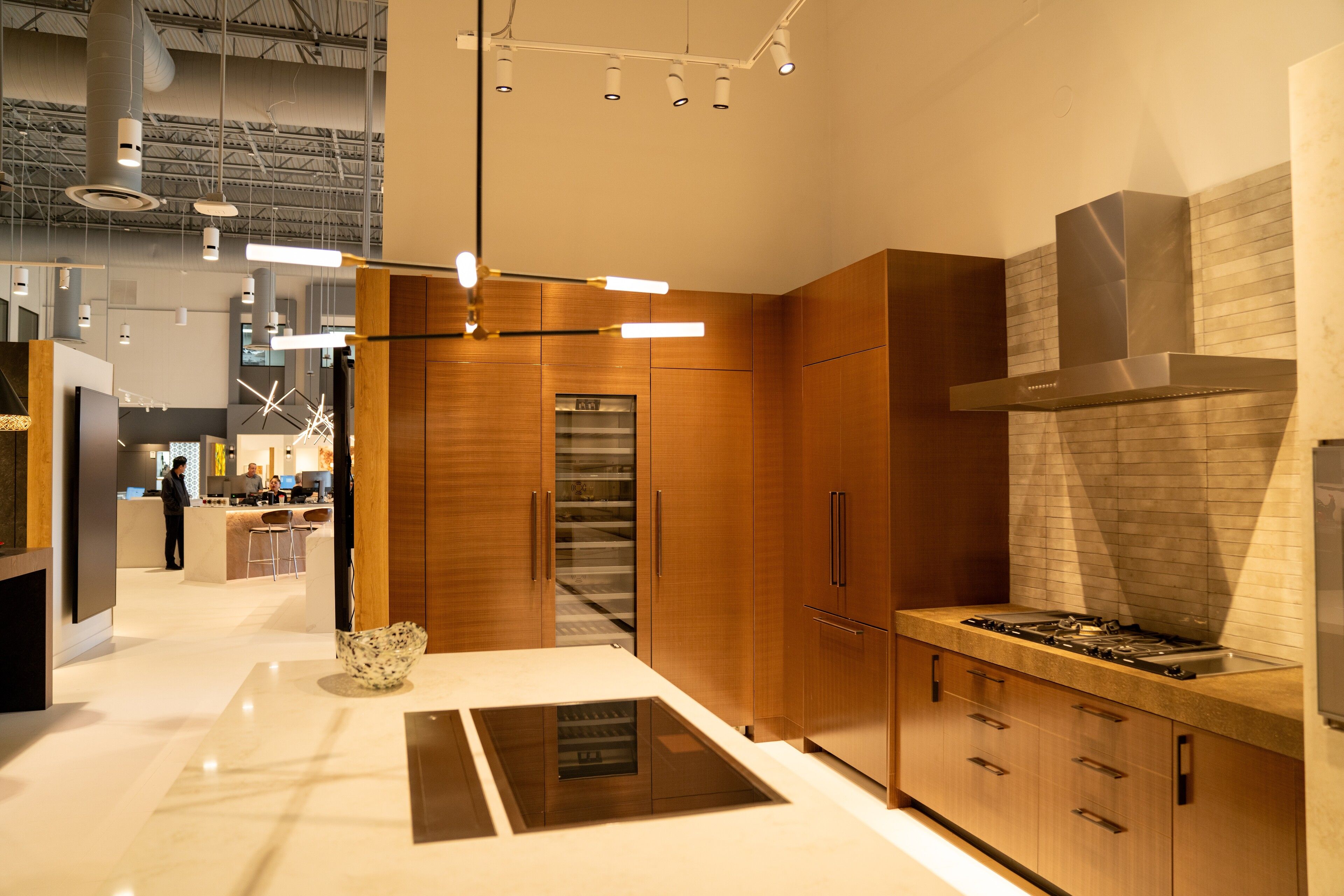 Warm walnut cabinetry with a white marble waterfall island and cooktop